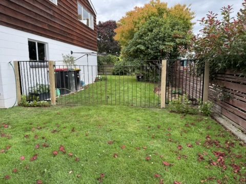 Black metal fence and gates between timber posts