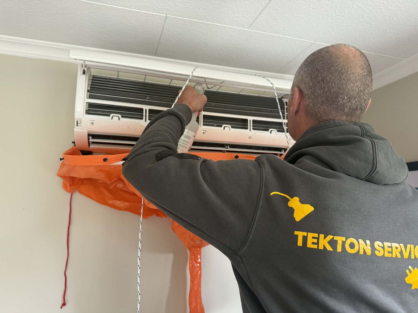 Tekton Services cleaning a heat pump indoor unit with a drain bag fitted