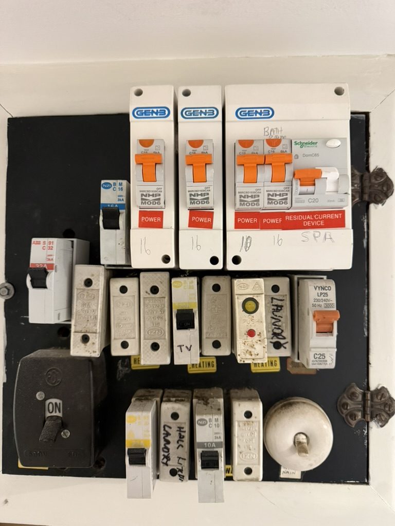 Old switchboard with a mix of ceramic fuses and add-on breakers